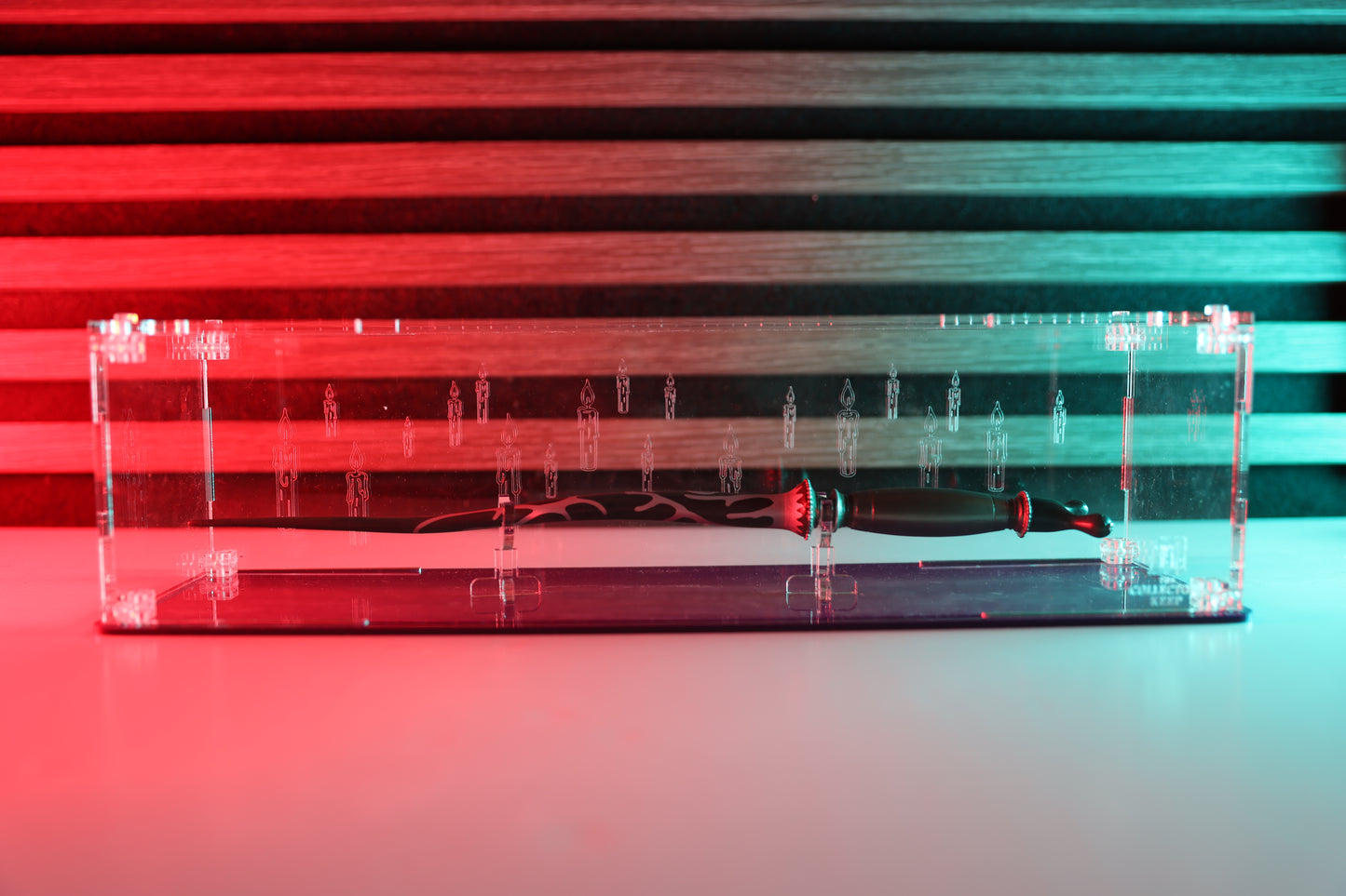 Clear acrylic wand display case with coloured base and candle engraving on the back.