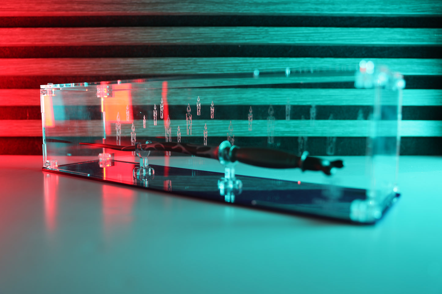 Clear acrylic wand display case with coloured base and candle engraving on the back.