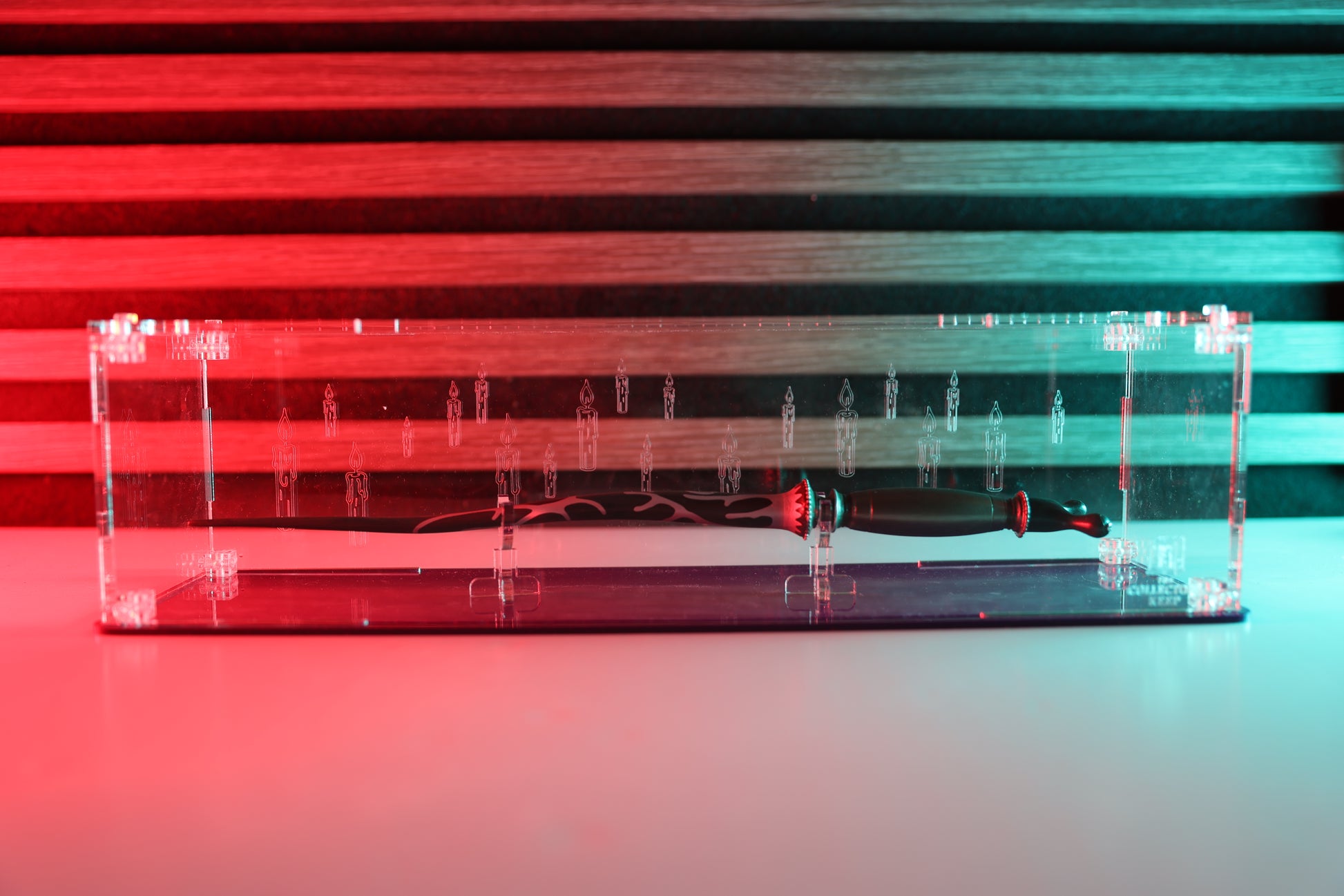 Clear acrylic wand display case with coloured base and candle engraving on the back.