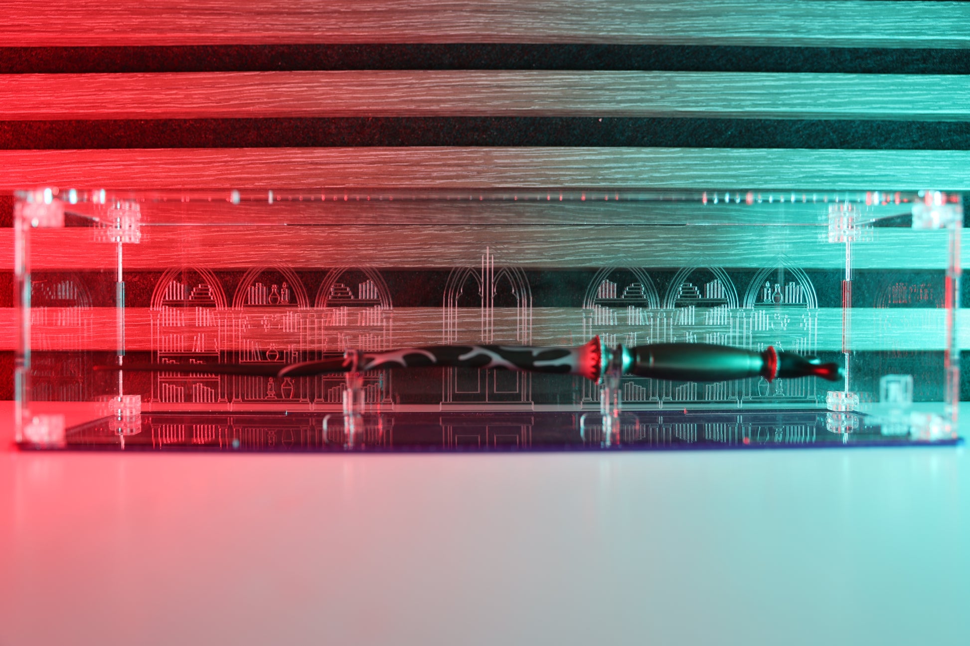 Clear acrylic wand display case with coloured base and library engraving on the back.