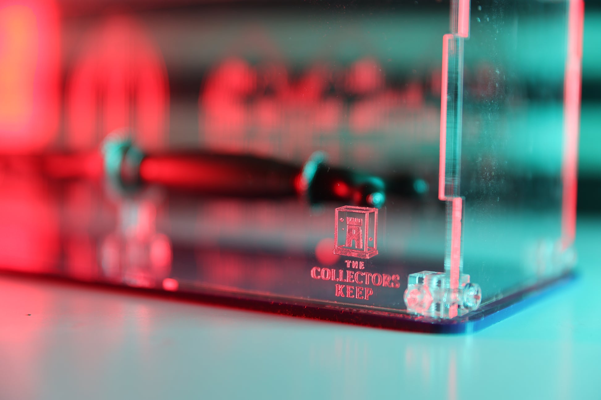 Clear acrylic display case with 'The Collector's Keep' branding on the front.