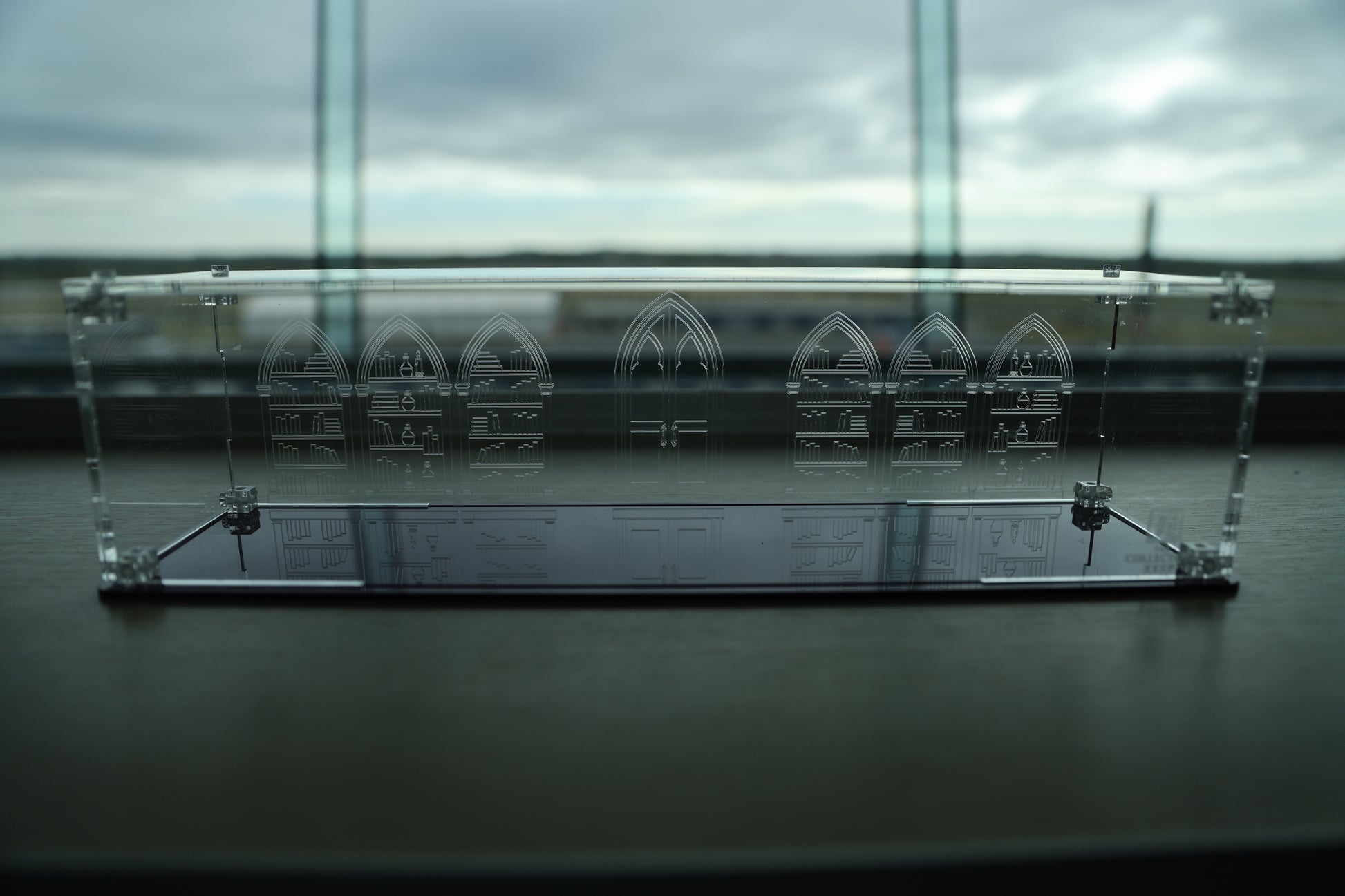Clear acrylic wand display case with coloured base and library engraving on the back.