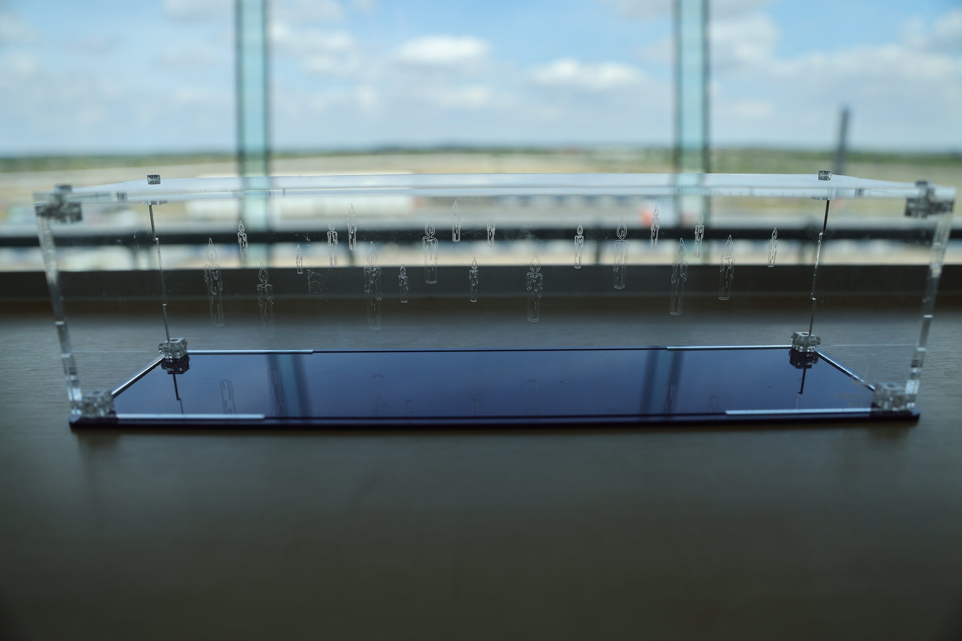 Clear acrylic wand display case with coloured base and candle engraving on the back.