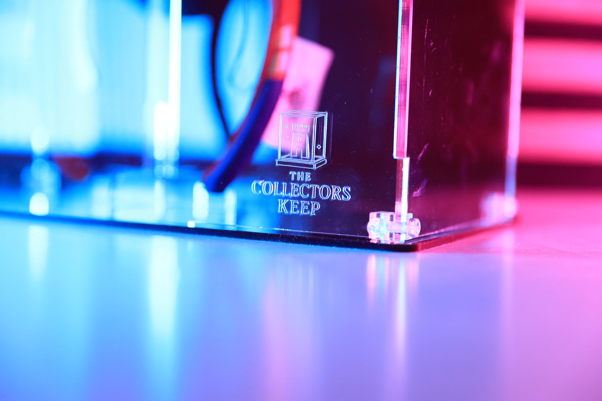 Clear acrylic display case with 'The Collector's Keep' branding on the front.