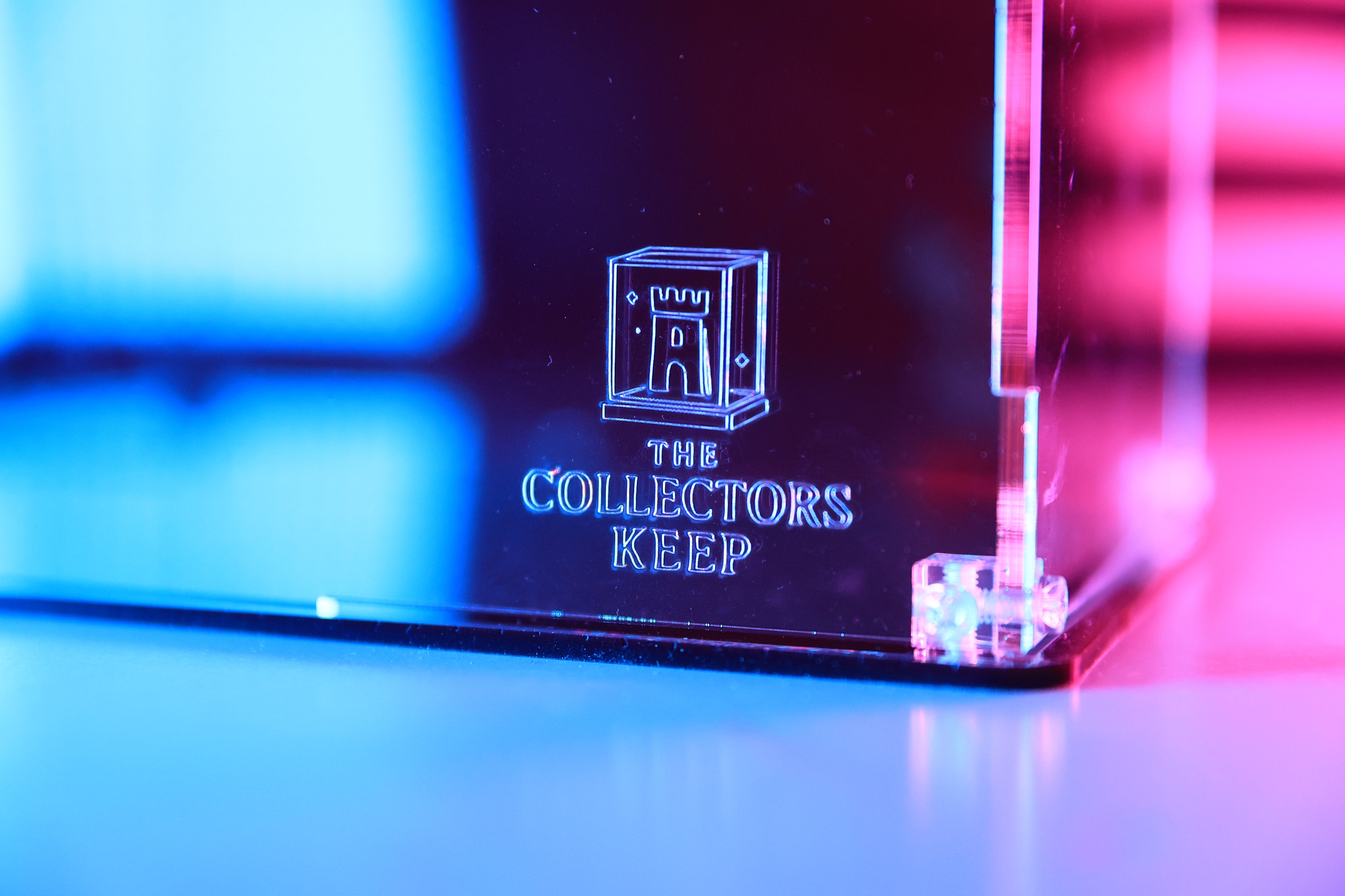 Acrylic display stand with 'The Collector's Keep' branding on the front.